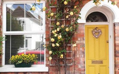 beautiful-yellow-front-door-with-floral-and-exposed-brick